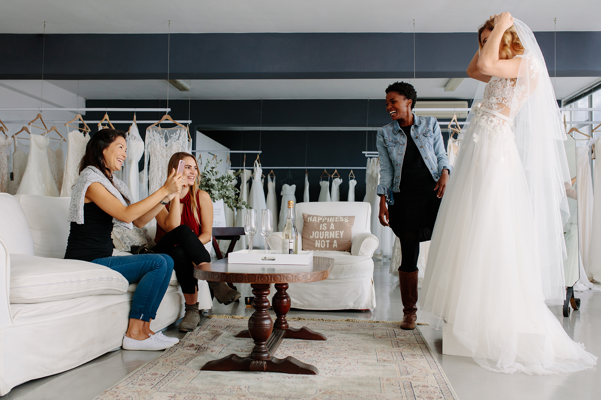 wedding boutique friends helping bride try on dress
